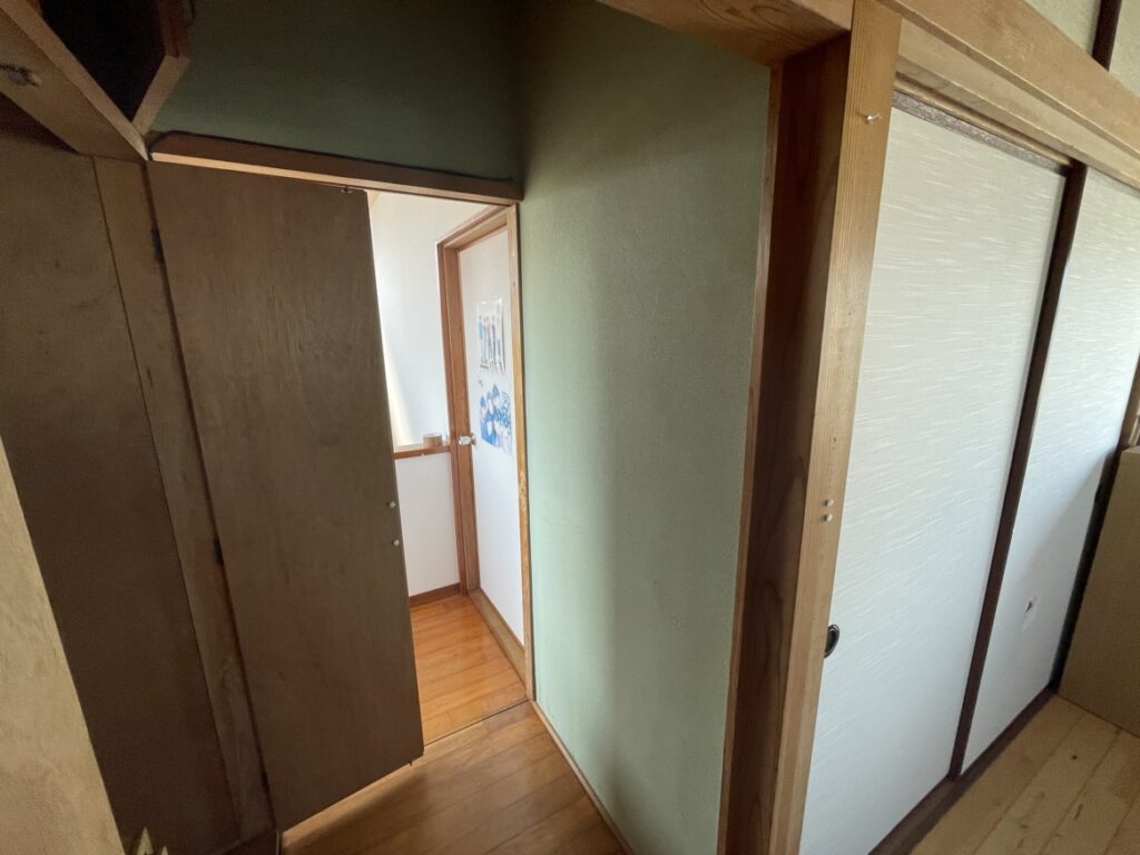 木製の引き戸が2枚並び、階段の手すりが左側に見える。